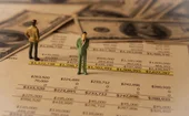 Tiny models of businessmen stand on some sheets of financial plan pages