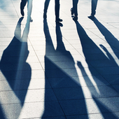 Long shadows of people standing on a pavement
