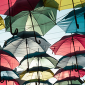 Multiple coloured umbrellas suspended in a sunny sky