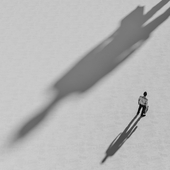 A large, long shadow is cast ominously next to a businessman