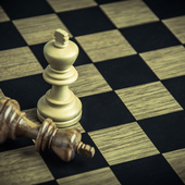 A chess board, with one standing white king and one fallen black king