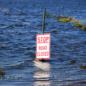 Sign saying ‘stop, road closed’ submerged in floodwater
