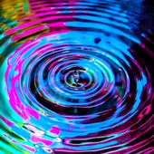 A droplet creates a ripple effect in multi-colours