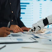 A robot points at some charts, helping humans to analyse the data 